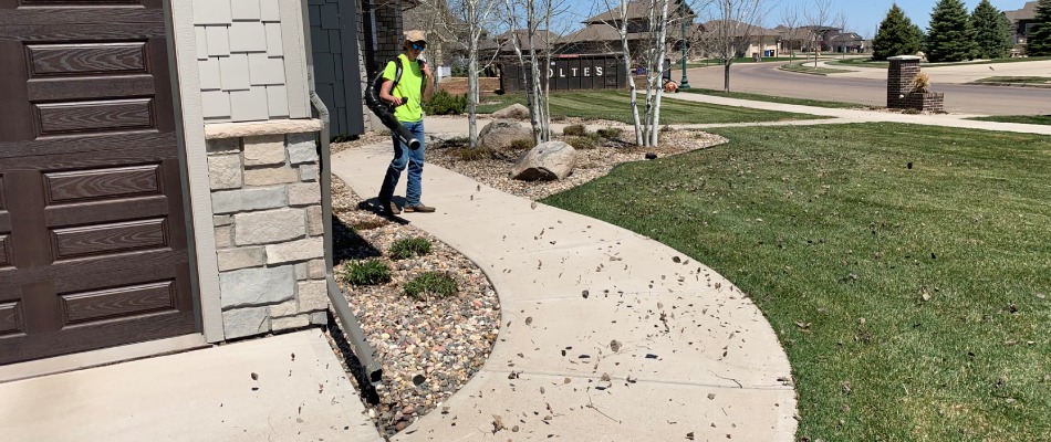 A professional blowing leaf debris off of walkway in Sioux Falls, SD.