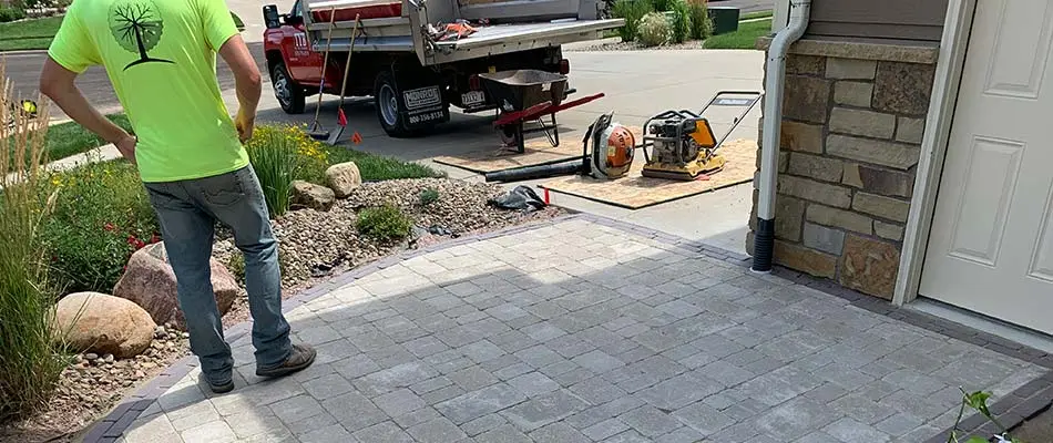 Landscape maintenance pros cleaning up a landscape bed and paver walkway in Sioux Falls, SD.